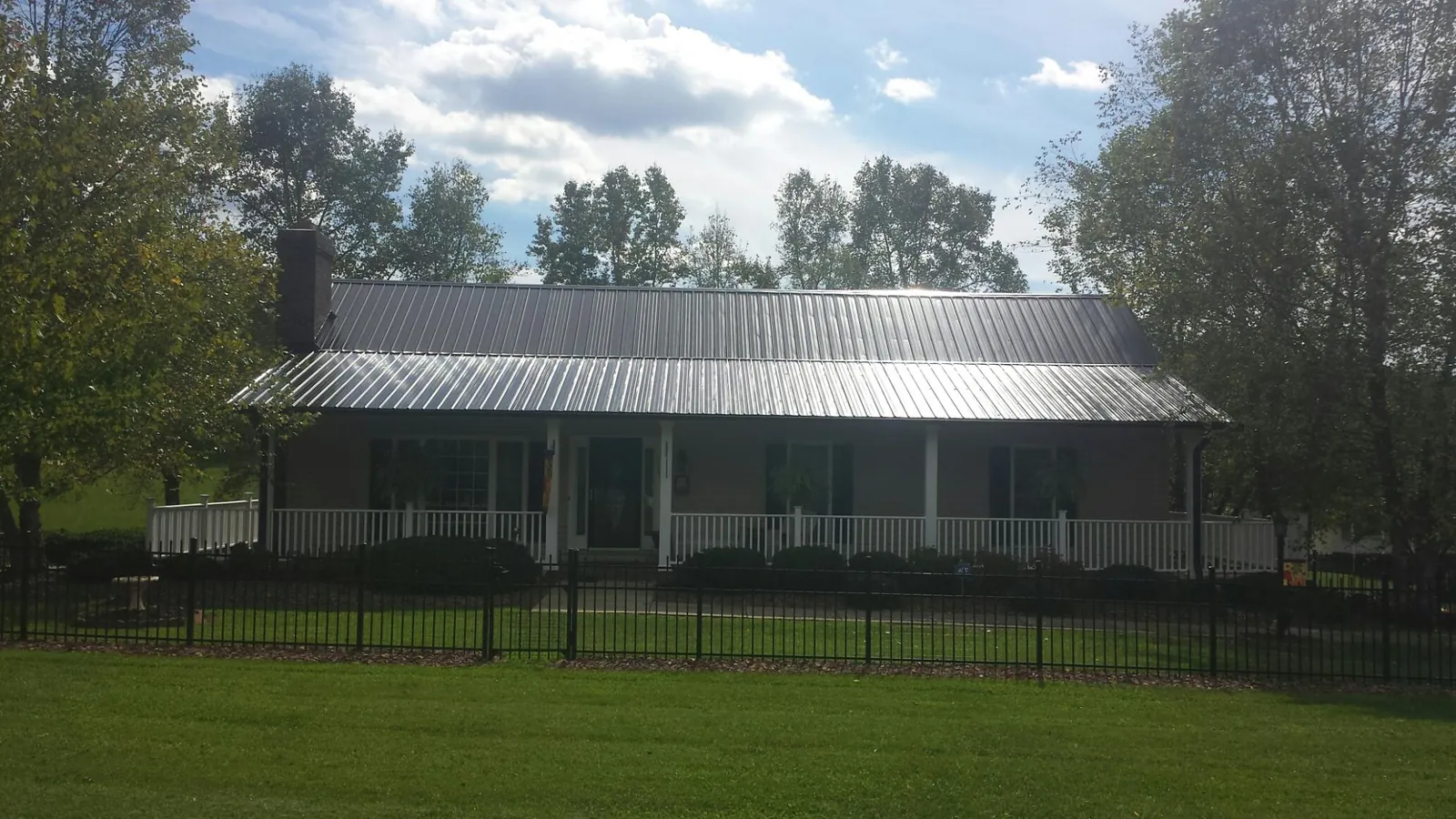 Gray metal roof on a brick ranch with a full width front porch — Gutter Guard Installation work by our crew in Sturgis