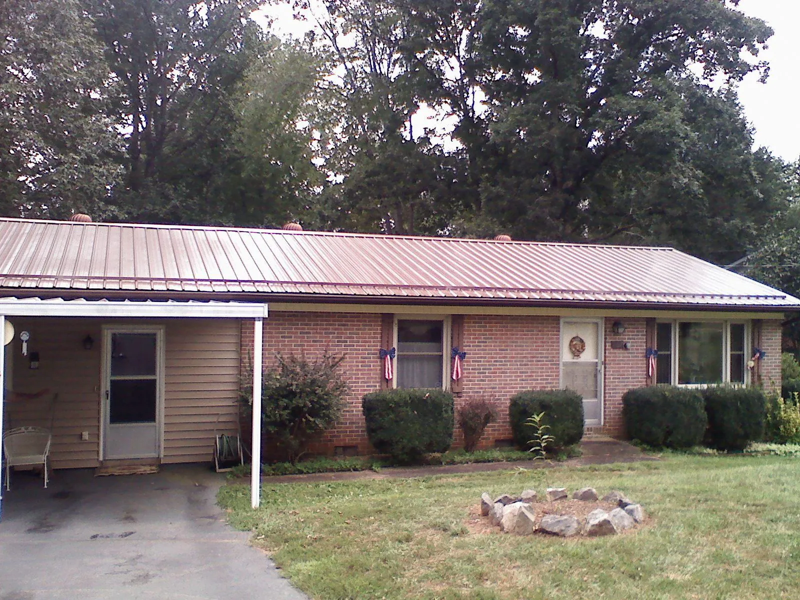 Bronze metal roof and carport on a brick ranch home — Roof Repair work by our crew in Sturgis